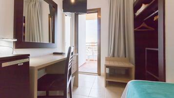 Une chambre d’hôtel équipée d’un bureau, d’une chaise, d’un lit, d’une télévision, d’une armoire et offrant une vue sur le balcon.