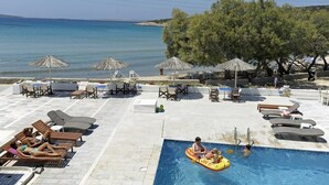 A poolside area with lounge chairs, umbrellas, and a swimming pool.