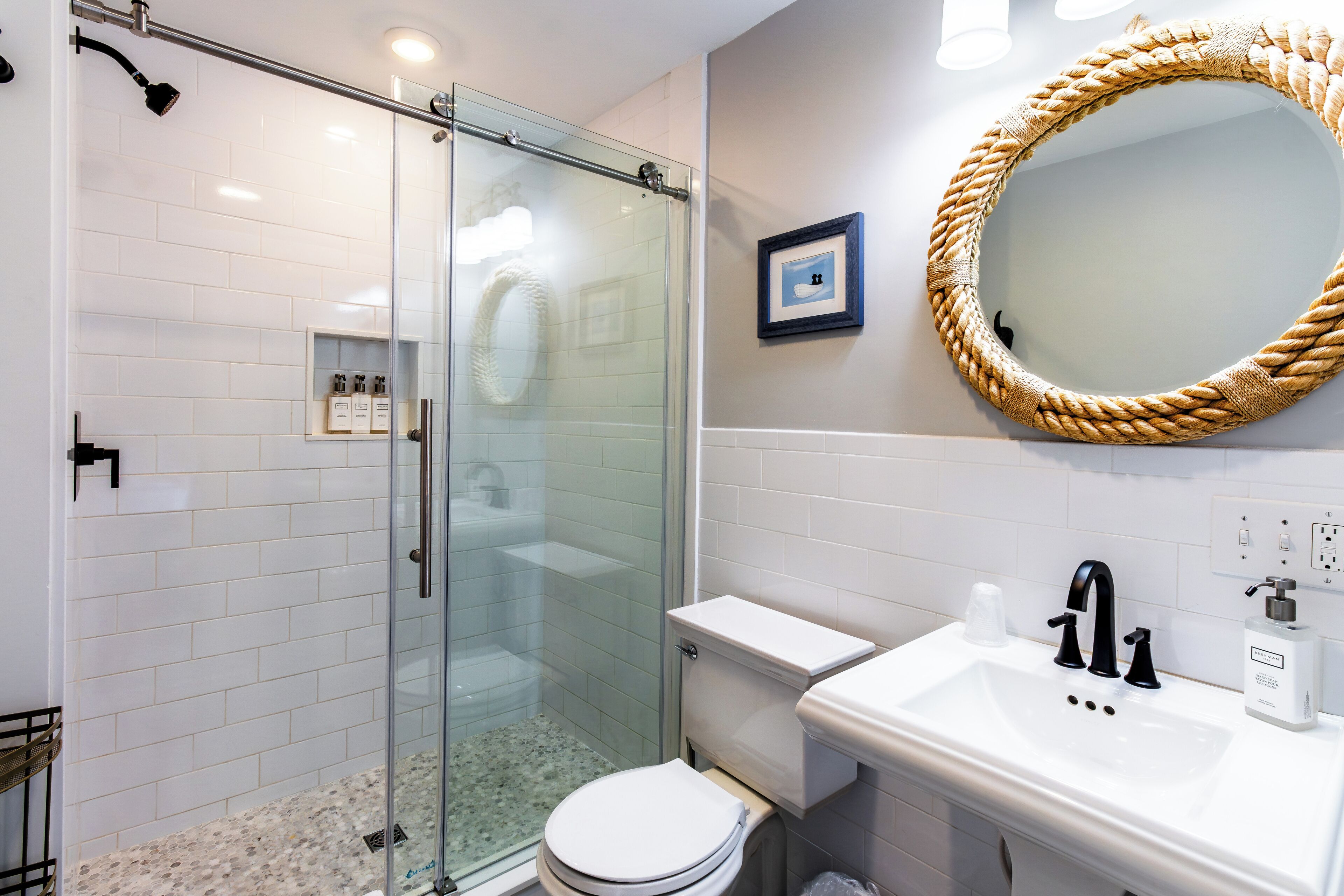 Een moderne badkamer met een douchecabine van glas, een wit toilet en een wastafel met spiegel.