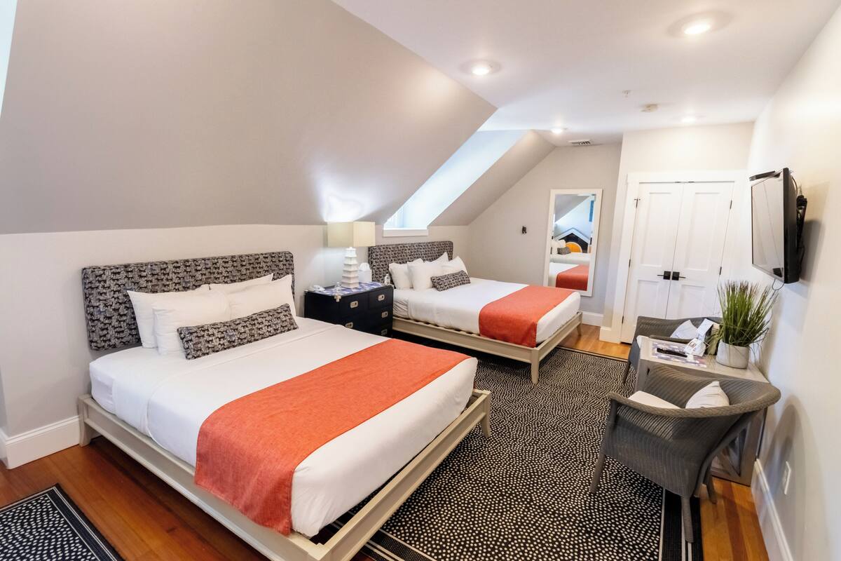 A bedroom with two beds, a desk, a chair, and a TV.