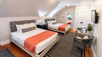 A bedroom with two beds, a desk, a chair, and a TV.