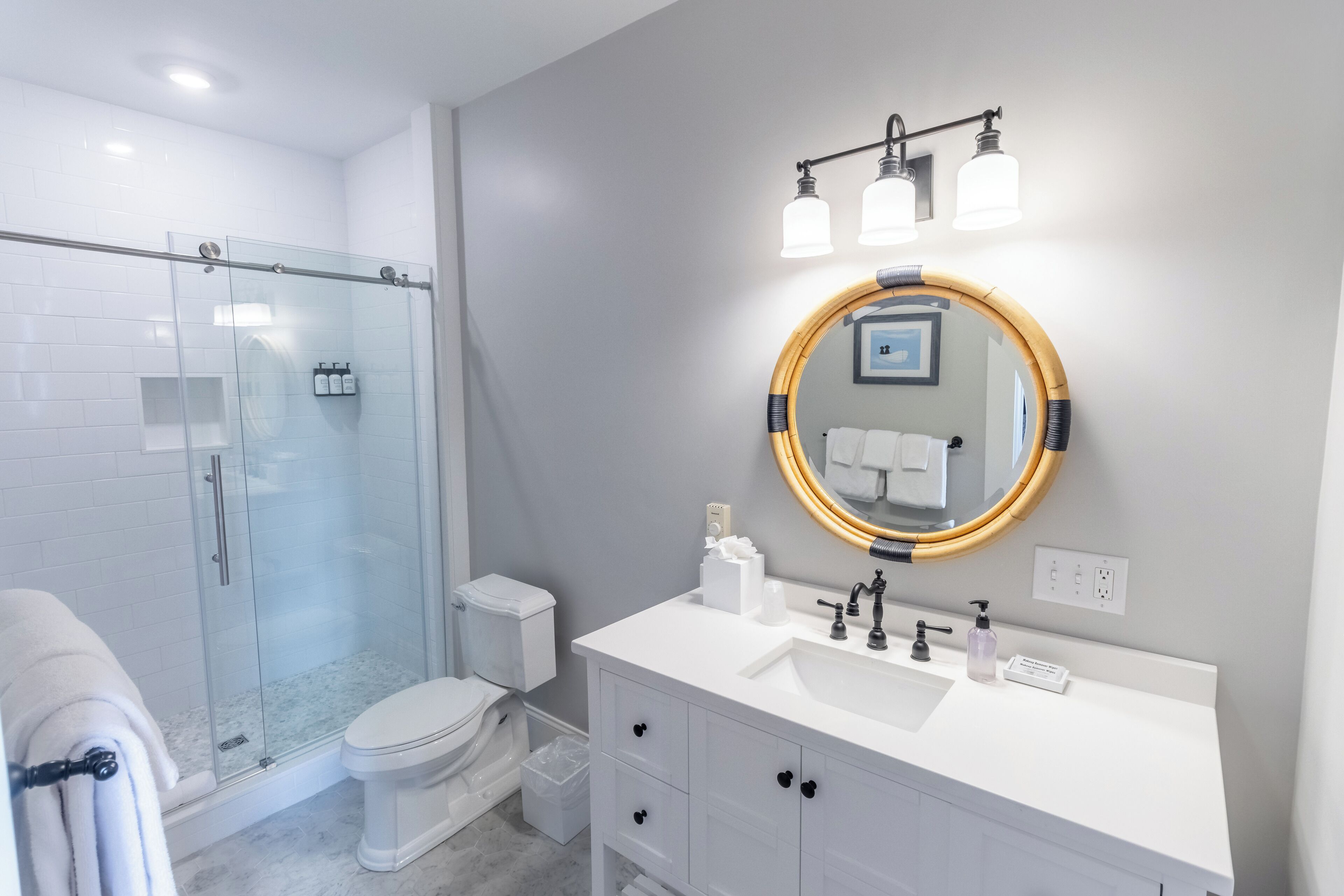 Un bagno moderno con doccia vetrata, un water, un lavandino con specchio e un porta asciugamani.
