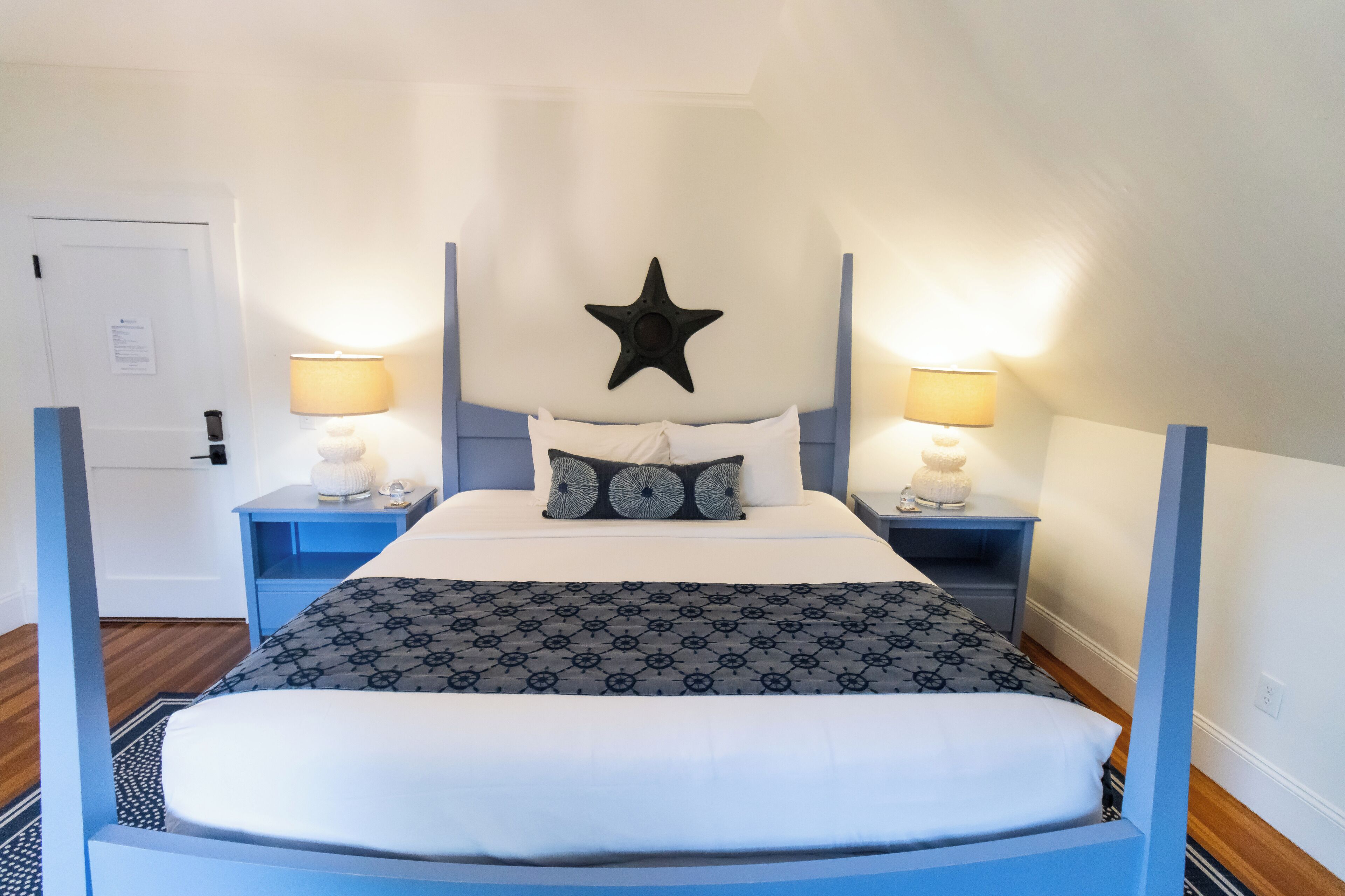 Un dormitorio ordenado con una cabecera en forma de estrella, una colcha estampada y dos lámparas de noche.