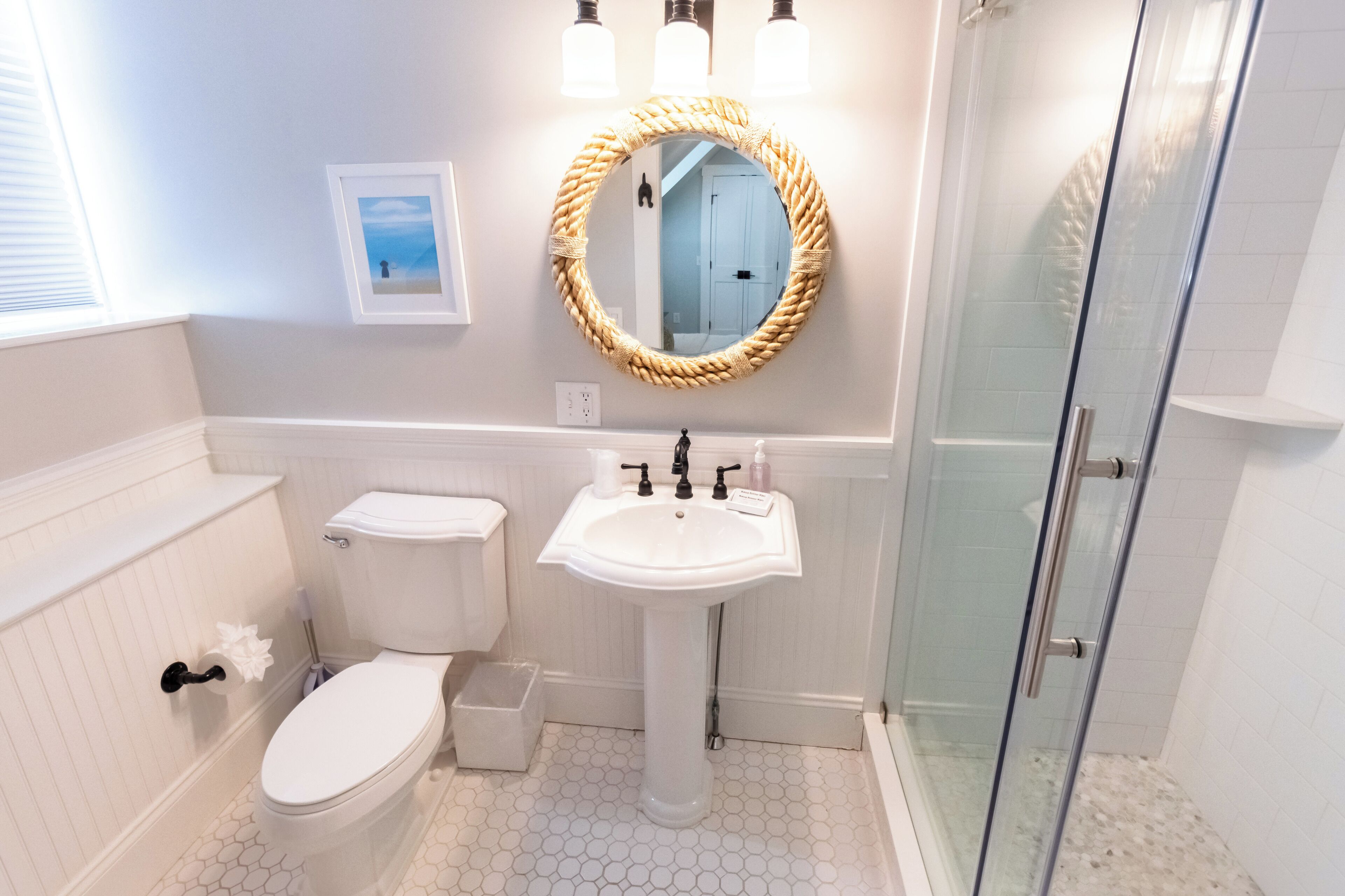A bathroom with a toilet, sink, and glass shower enclosure.
