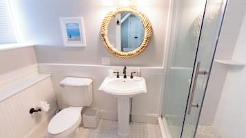 A bathroom with a toilet, sink, and glass shower enclosure.