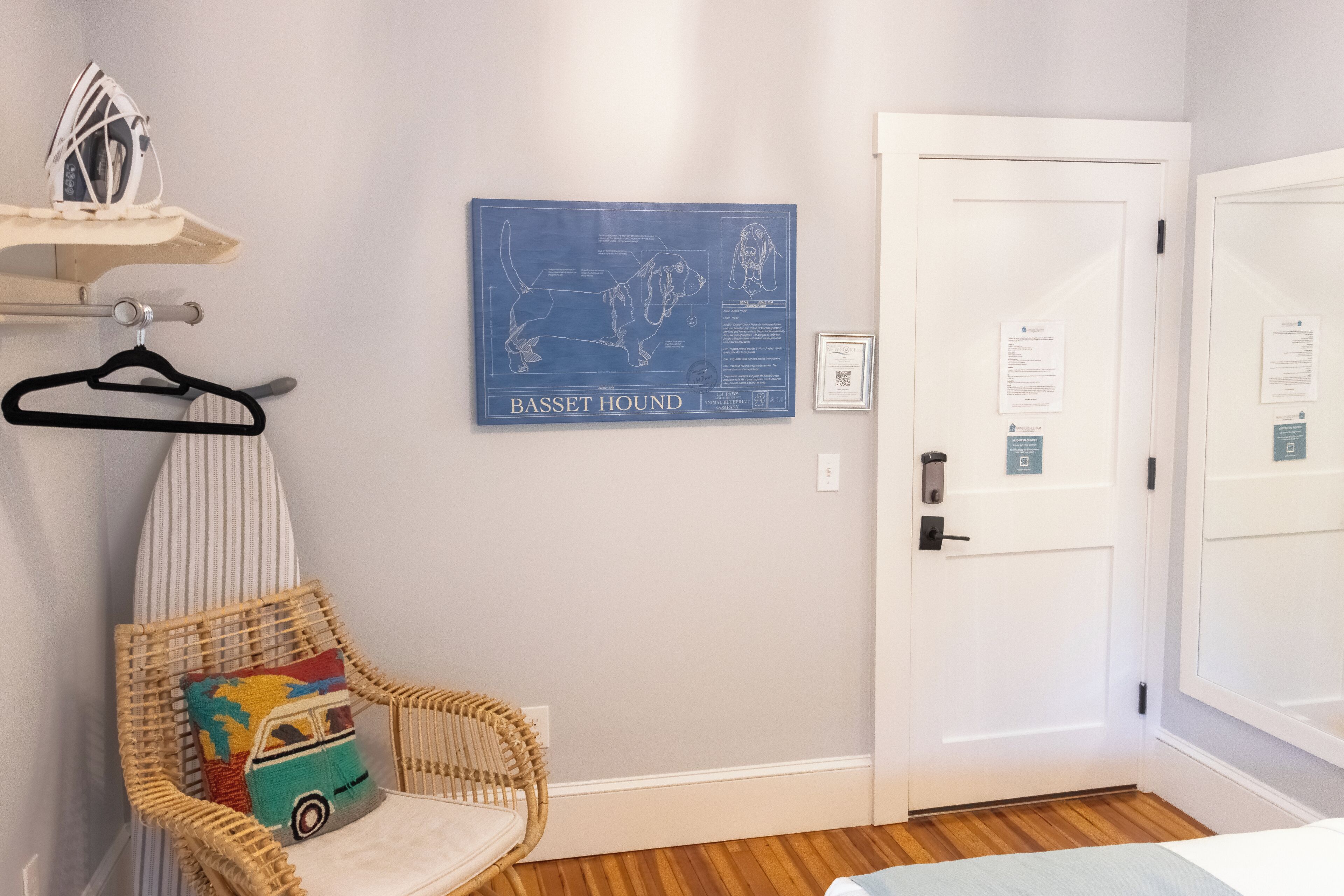 A room with a wicker chair, a map of a dog breed, and a white door.