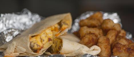 A burrito and tater tots on foil.