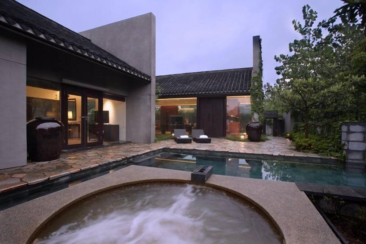 A modern house with a swimming pool, outdoor seating, and a hot tub.