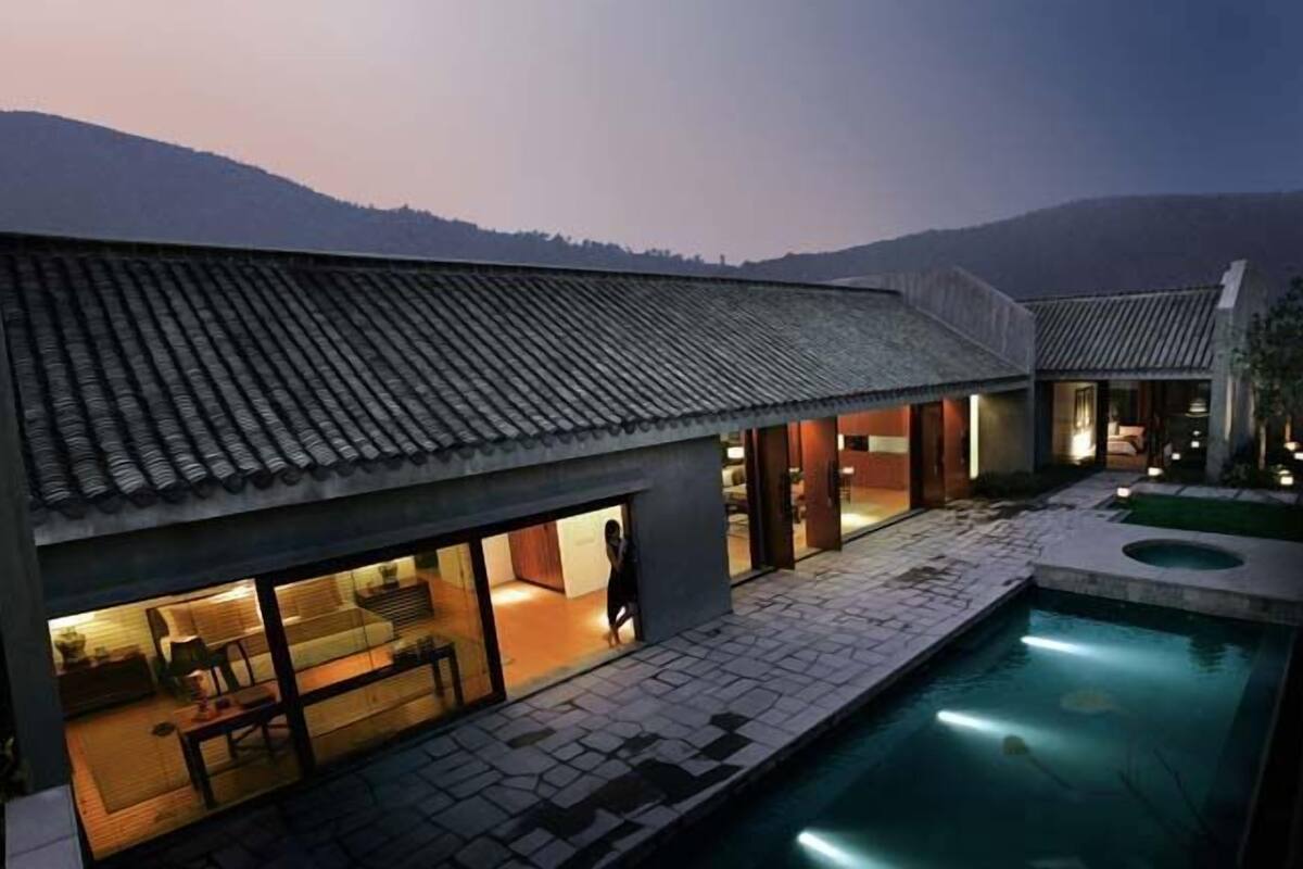 A modern house with a swimming pool, large windows, and a tiled roof.