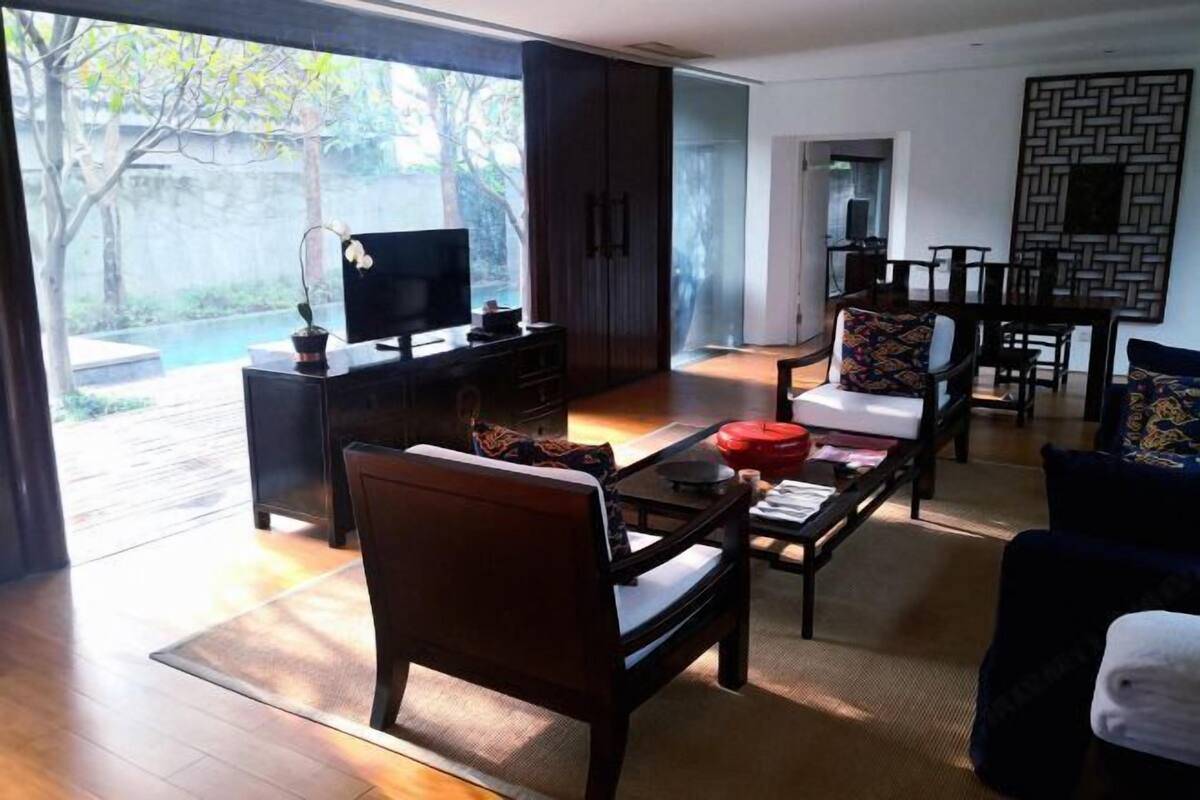A modern living room with a TV, sofa, coffee table, and a view of a garden.