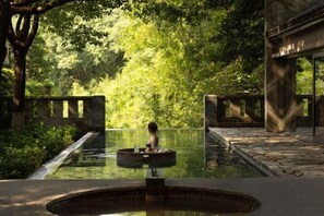 A serene outdoor pool area with a person relaxing, surrounded by lush greenery and traditional architecture. - Kayumanis Nanjing Private Villa & Spa (Nanjing)