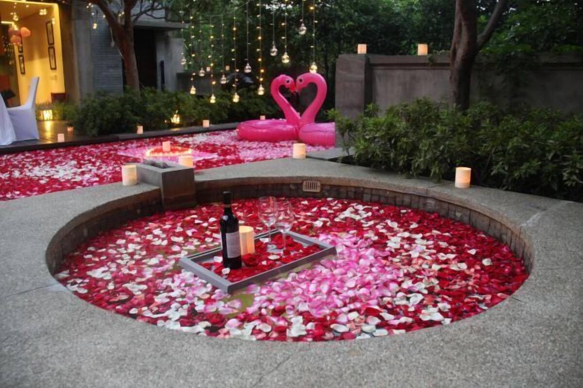 A circular seating area with rose petals, candles, and a bottle.