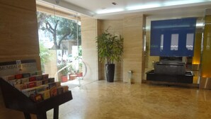 A lobby with a marble floor, a reception desk, a potted plant, and a sign reading "MUMBAI & BEYOND". - Ascot Hotel (Mumbai)