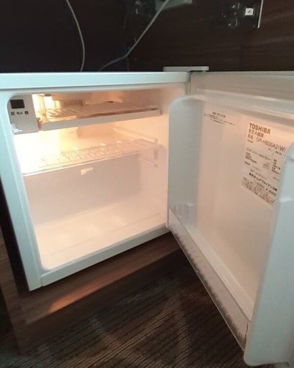 An open refrigerator with a Toshiba label, a control panel, and a freezer compartment.