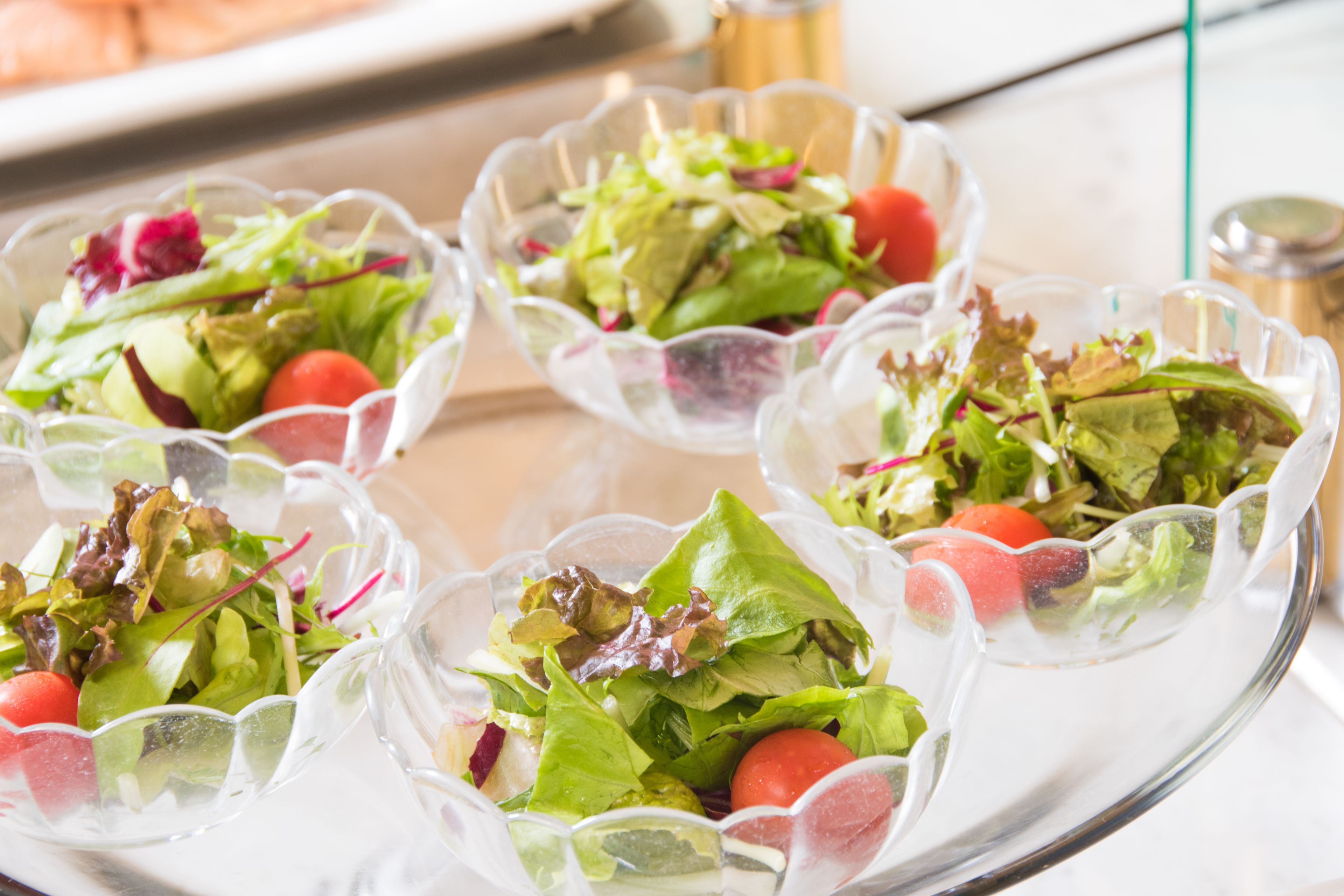 Un plateau avec des bols en verre transparent contenant des salades.