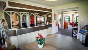 Un vestíbulo de hotel con mostrador de recepción, zona de estar y bar.