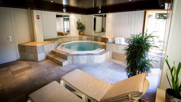 Un área de spa con una bañera de hidromasaje, asientos y una escalera que conduce a un balcón.
