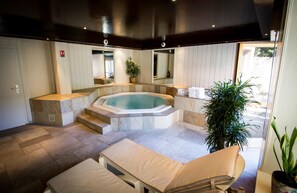 Een wellnessruimte met een jacuzzi, zitplaatsen en een trap naar een balkon.
