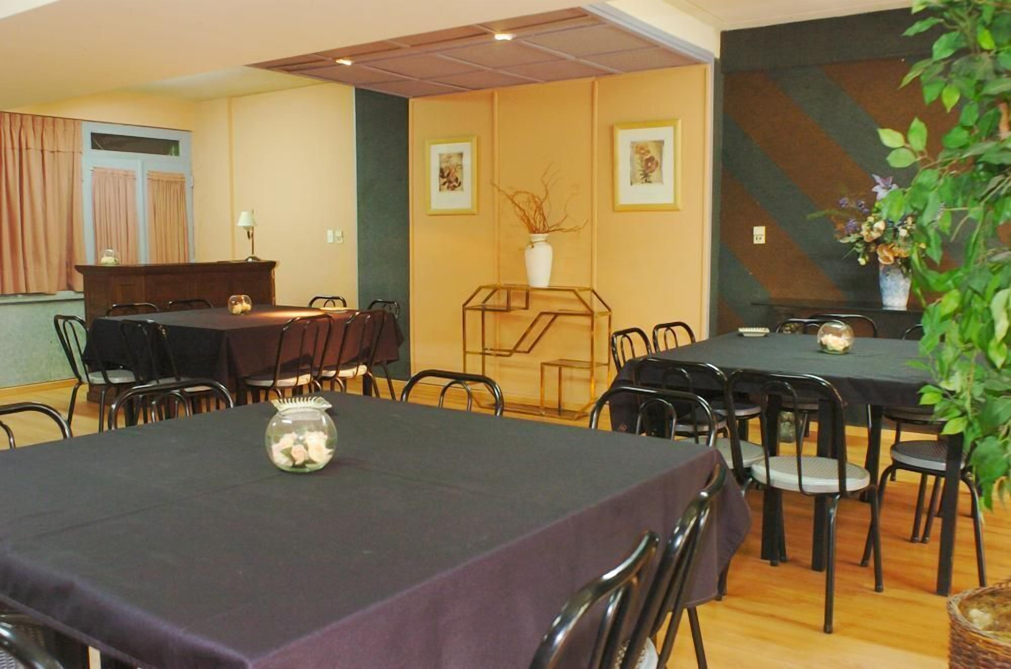 A dining area with tables and chairs, a decorative vase, and framed artwork on the walls.
