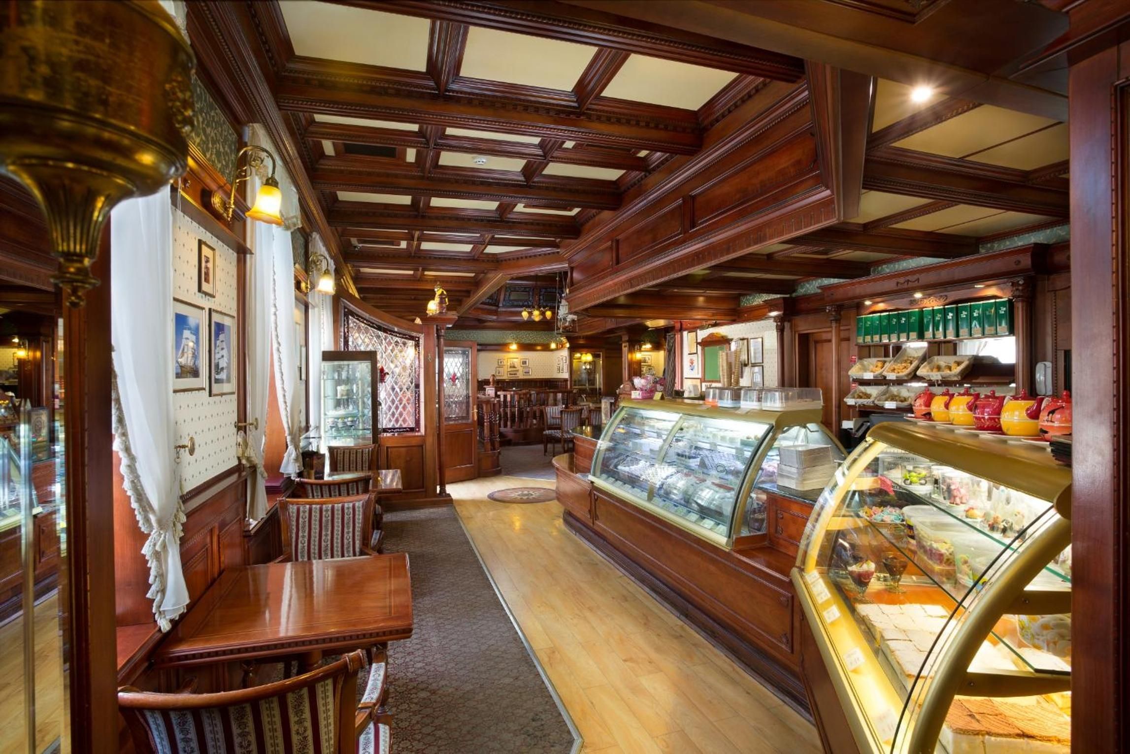 A vintage interior with wooden paneling, a counter with baked goods, and a display case with pastries.
