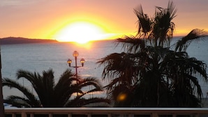 A sunset over a body of water with palm trees in the foreground. - Azur (Nice)