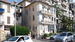 A hotel with balconies, a sign indicating it's a hotel, and a street with cars. - Azur (Nice)
