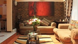 Una sala de estar acogedora con una pared de ladrillo, un reloj y un conjunto de sofás.