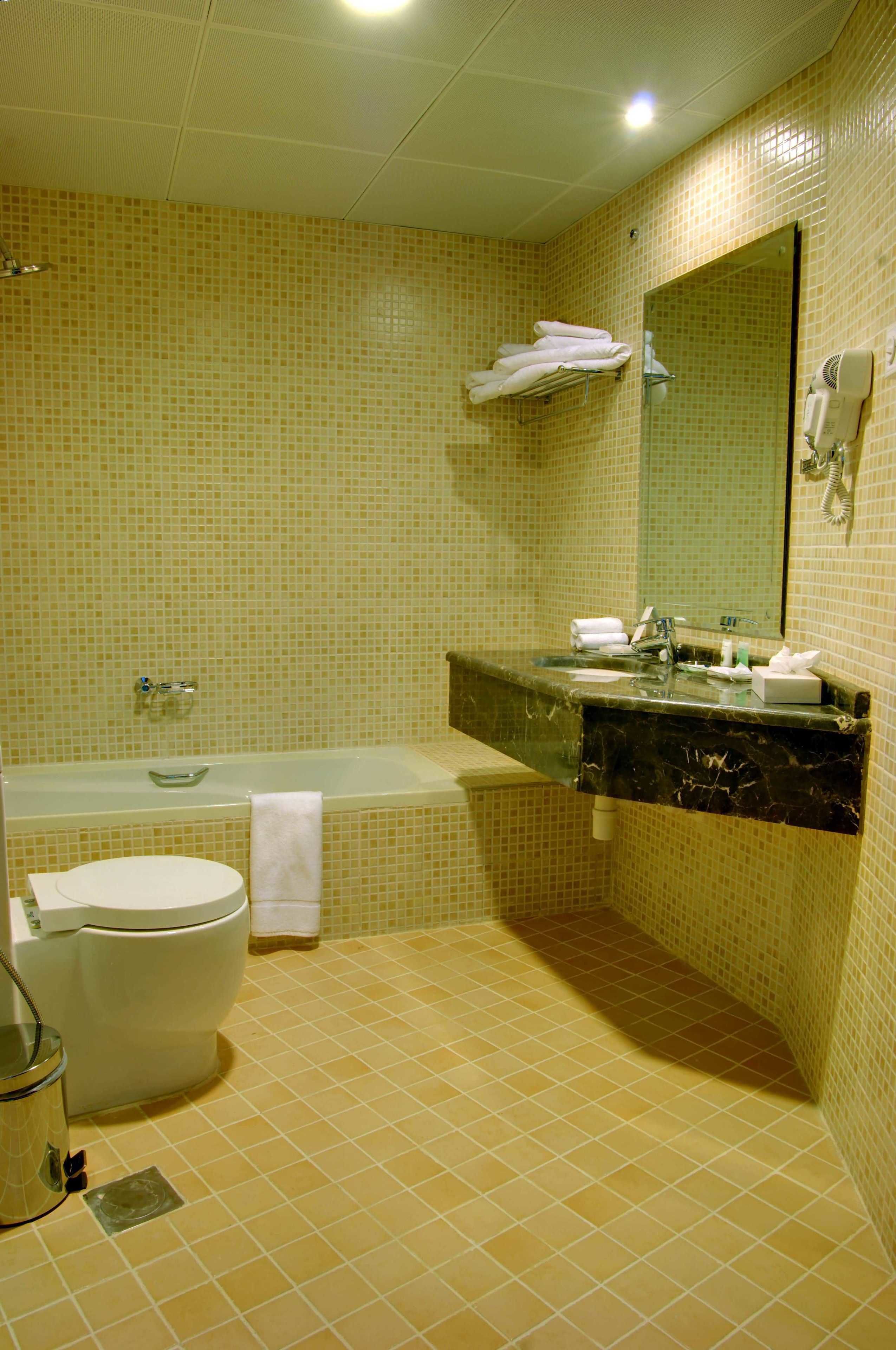 Un baño con inodoro, bañera, lavamanos y espejo.
