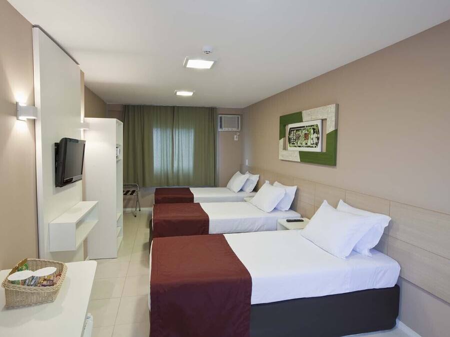 Habitación de hotel con dos camas, un televisor, una mesita con una cesta y un cuadro colgado en la pared.
