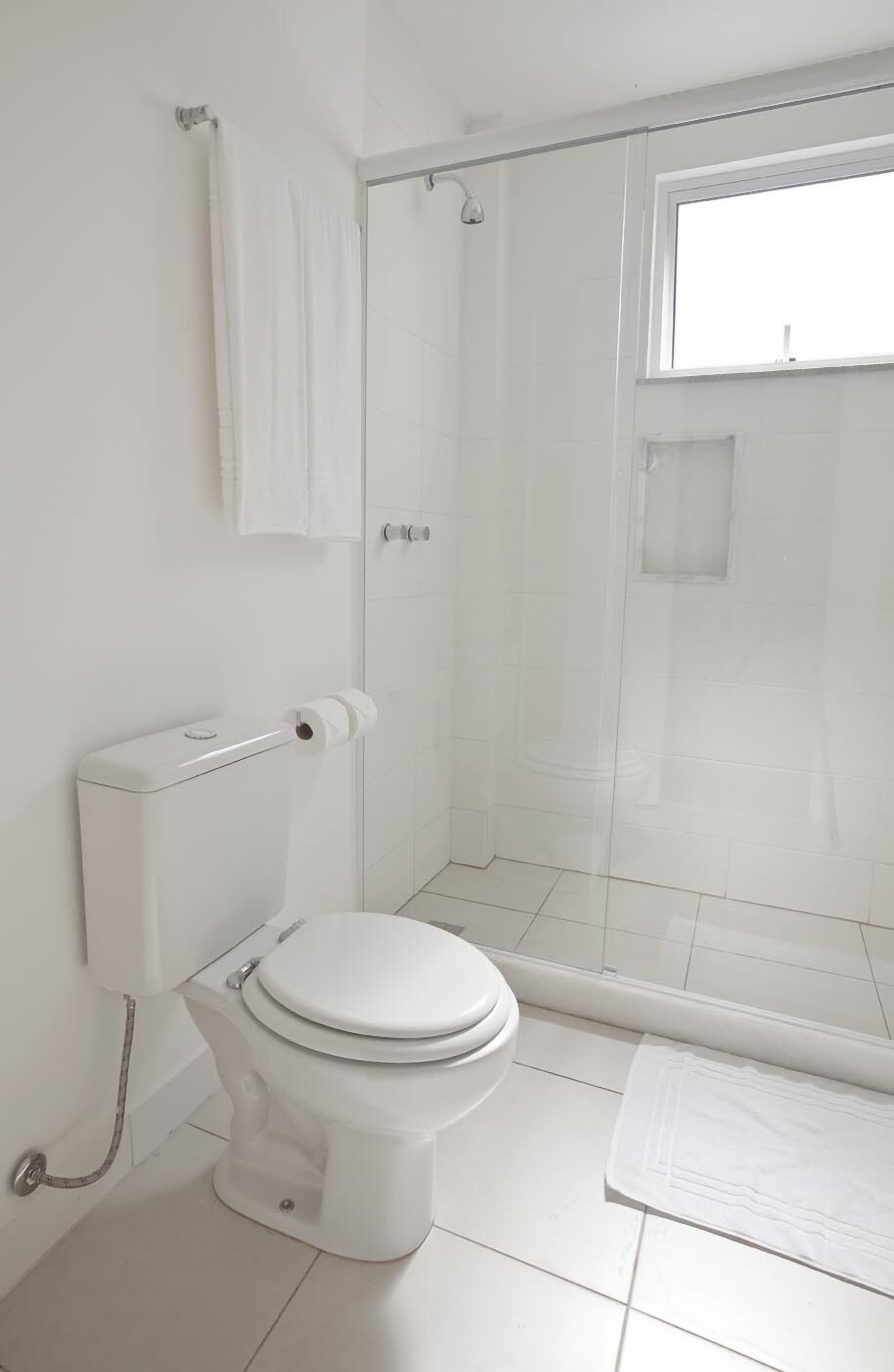 Une salle de bain comprenant des toilettes, un espace douche et une fenêtre.