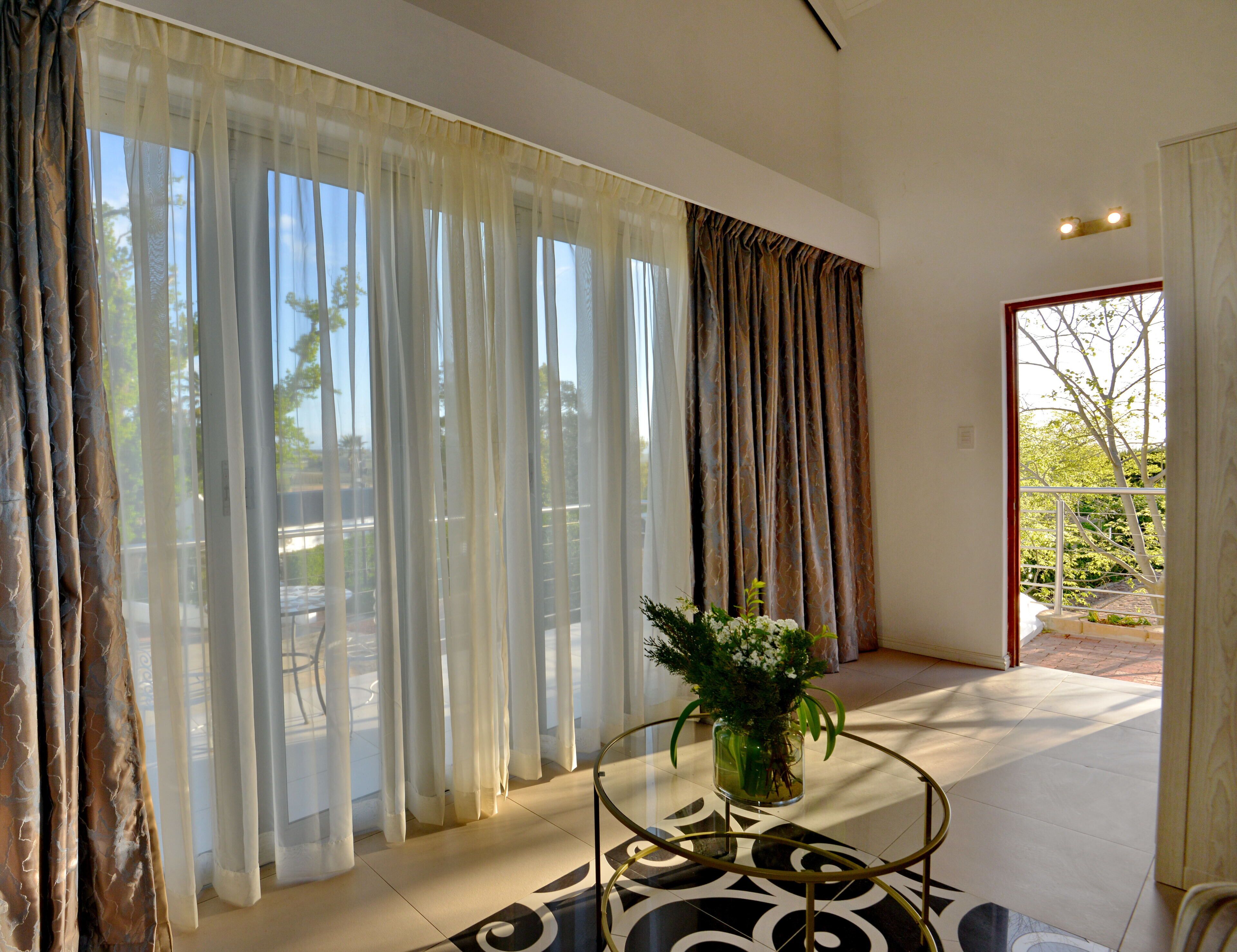 A room with large windows, a glass-top table, and a potted plant.