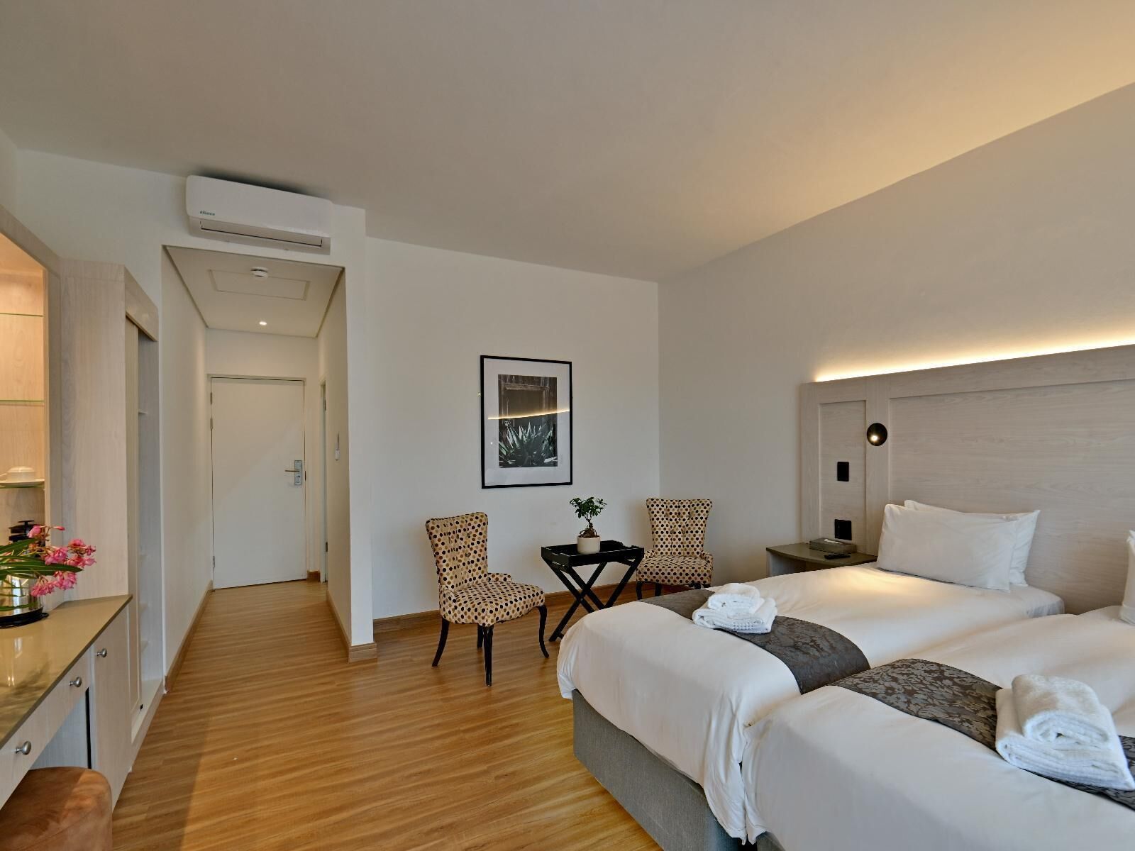 A hotel room with a bed, two chairs, a small table, and a picture on the wall.