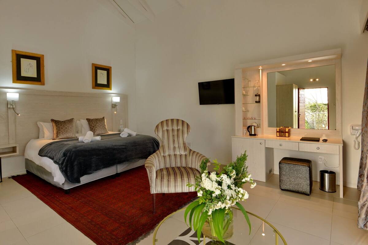 Een slaapkamer met een bed, een stoel, een bureau, een spiegel en een televisie.