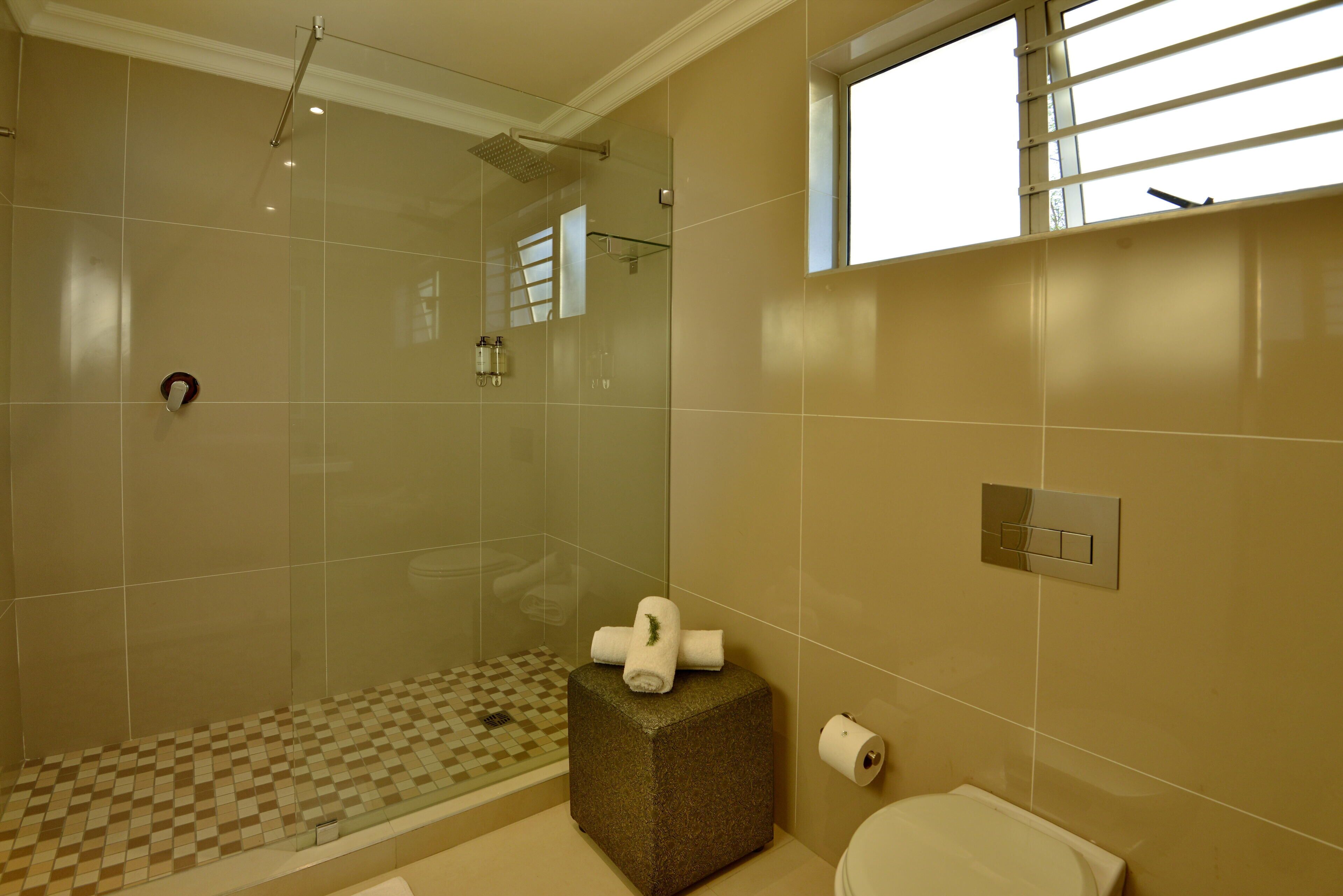 A bathroom with a glass shower enclosure, a checkered floor, a towel rack, and a toilet.