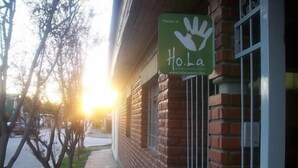 A brick building with a green sign that reads "Member of Hola" and a website address. - Neuquen Hostel Portal de Sueños (Neuquen)