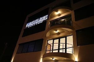 Un hotel con un letrero llamativo, varios balcones y grandes ventanales.