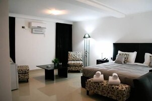Una habitación de hotel moderna con una cama grande, un escritorio, una silla y una lámpara de pie.