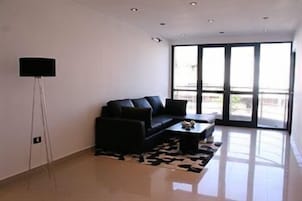 Una sala de estar moderna con un sofá negro, una mesa de centro y una lámpara de pie.
