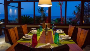 A dining table set for six with a view of the ocean at dusk. - Kaliviani Traditional Hotel (Kissamos)