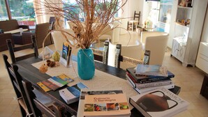 A dining table with a blue vase, books, and a decorative branch. - Sa Fiorida Apartments (Valledoria)
