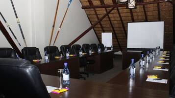 A conference room with a long table, black leather chairs, water bottles, and a whiteboard.