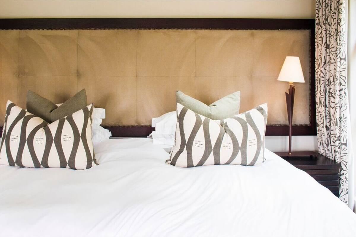 A neatly made bed with striped pillows, a tufted headboard, and two bedside lamps.