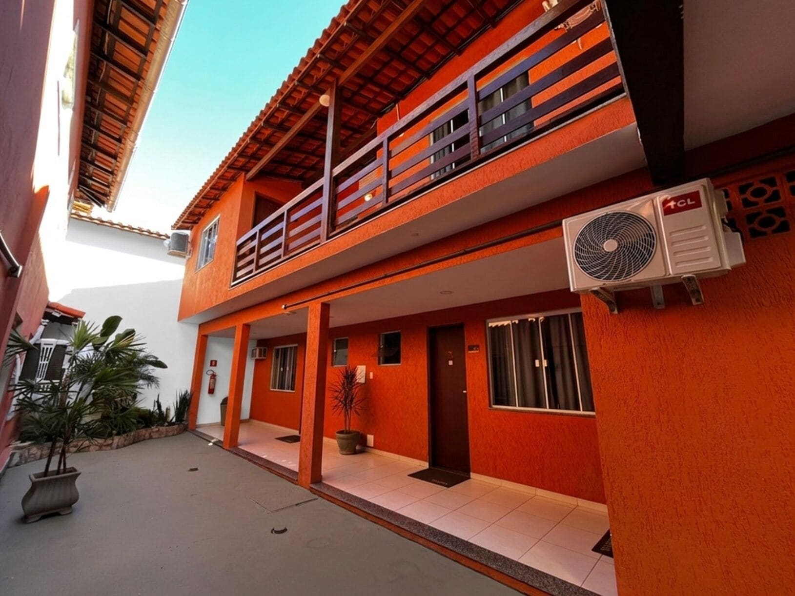 A two-story building with a balcony, an air conditioning unit, and a potted plant.