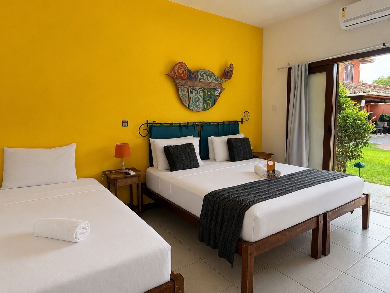 Habitación de hotel con dos camas, un adorno en la pared y vistas al exterior.