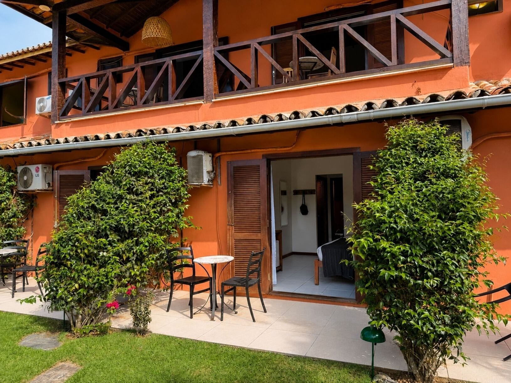 A two-story building with a balcony, outdoor seating area, and a door leading to an interior space.