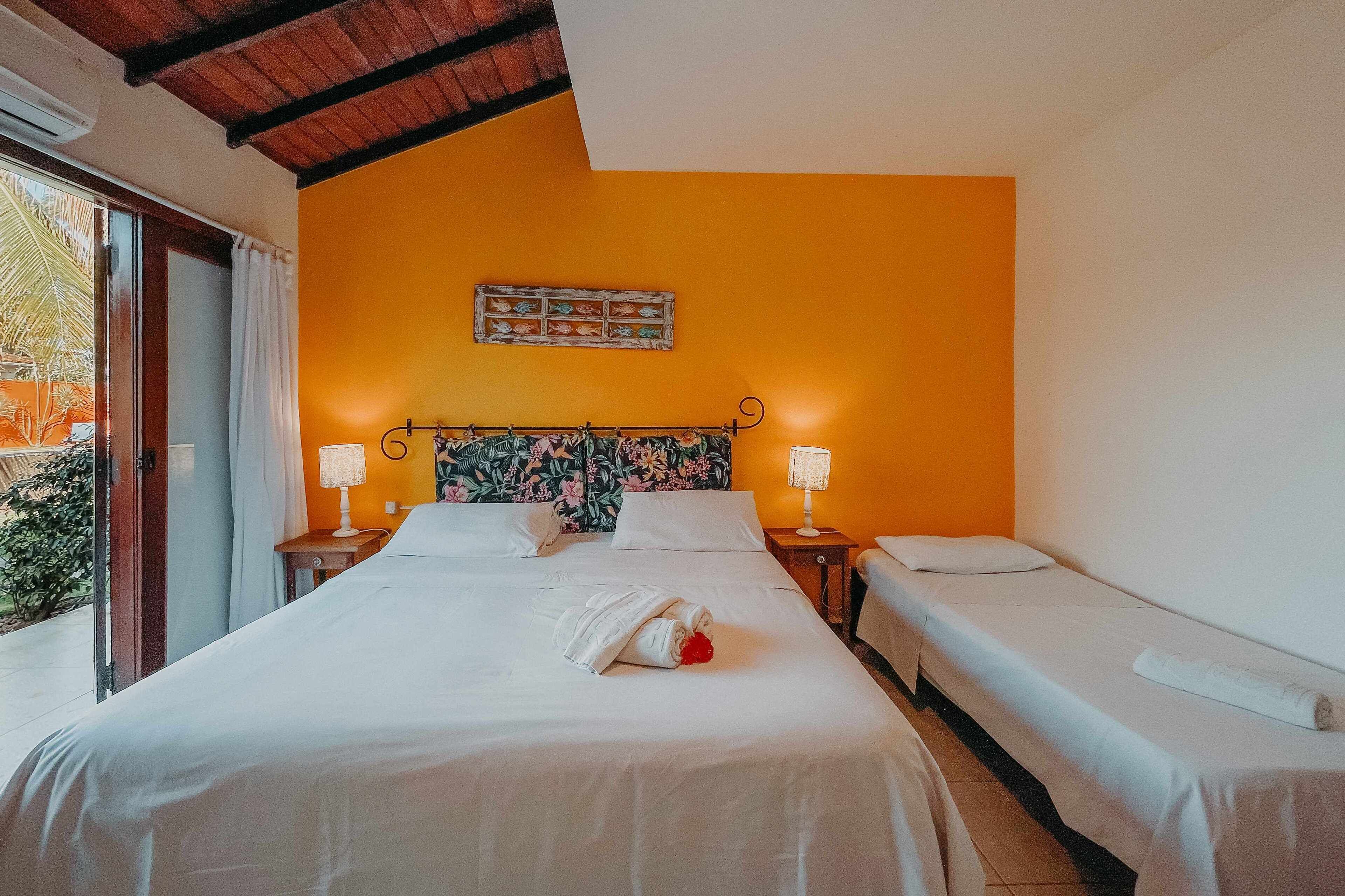 Een hotelkamer met een bed, twee nachtkastjes, gordijnen voor het raam en een kunstwerk aan de muur.