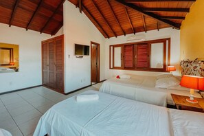 A hotel room with two beds, a wooden ceiling, a TV, and a window with shutters. - Pousada Sable Dor (Búzios)