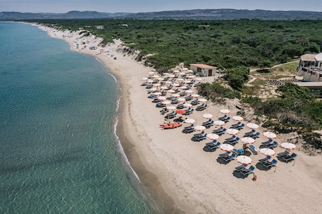 On the beach, sun-loungers, beach umbrellas. MClub Del Golfo
