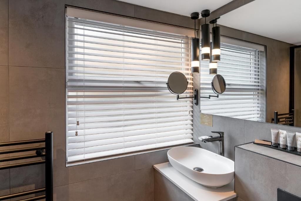 A modern bathroom with a large window, a vessel sink, and a mirror with integrated lighting.