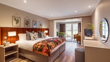 Habitación de hotel moderna con una cama grande, televisión, escritorio y baño a la vista a través de una puerta abierta.